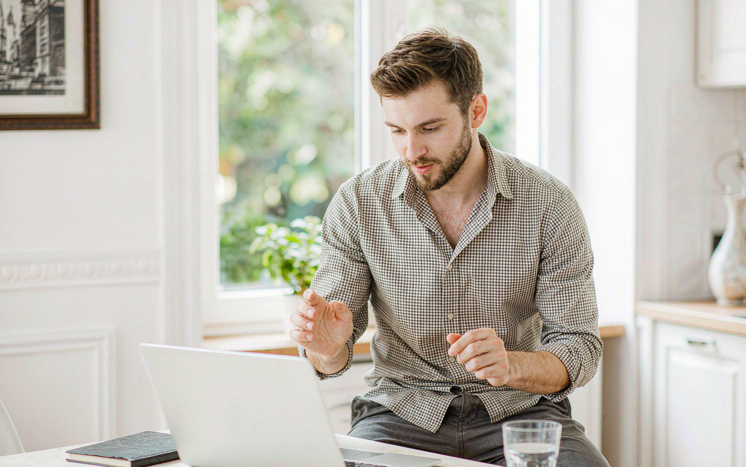 Freelancer reviewing a tax form on his laptop at a bright kitchen table